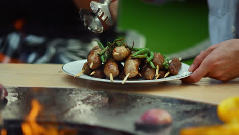 hombre desconocido poniendo verduras en un plato afuera. hombre chef usando fórceps al aire libre