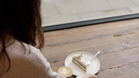 woman relaxing in a coffee shop with cake and coffee.