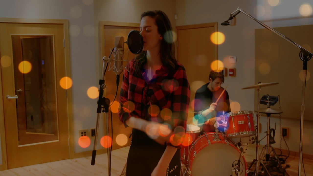 Vocalist singing into mic and drummer playing drums in recording studio, with animated sound waves