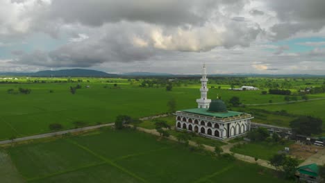 mezquita musulmana en la tierra de hierba, hierba verde, fondo de montaña tailandia, disparo aéreo de avión no tripulado en órbita lenta a la derecha, día claro día nublado