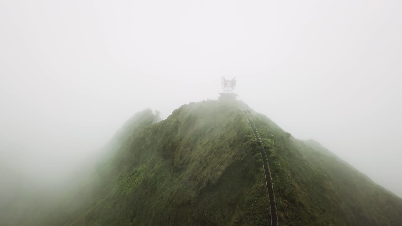 Aerial shot of clouds rolling over the top of the Haiku Stairs Trail, or Stairway to Heaven, on Oahu.