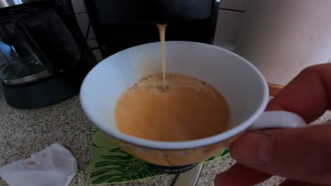 punto de vista: una persona hace café en la máquina, luego se da la vuelta para beberlo en la mesa