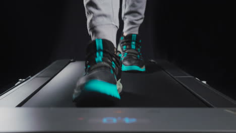 Static-frontal-close-up-shot-of-a-man's-feet-walking-on-a-treadmill