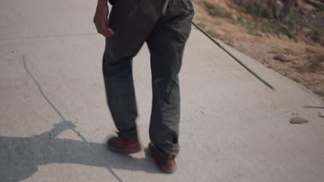 older man walking on a road with a stick