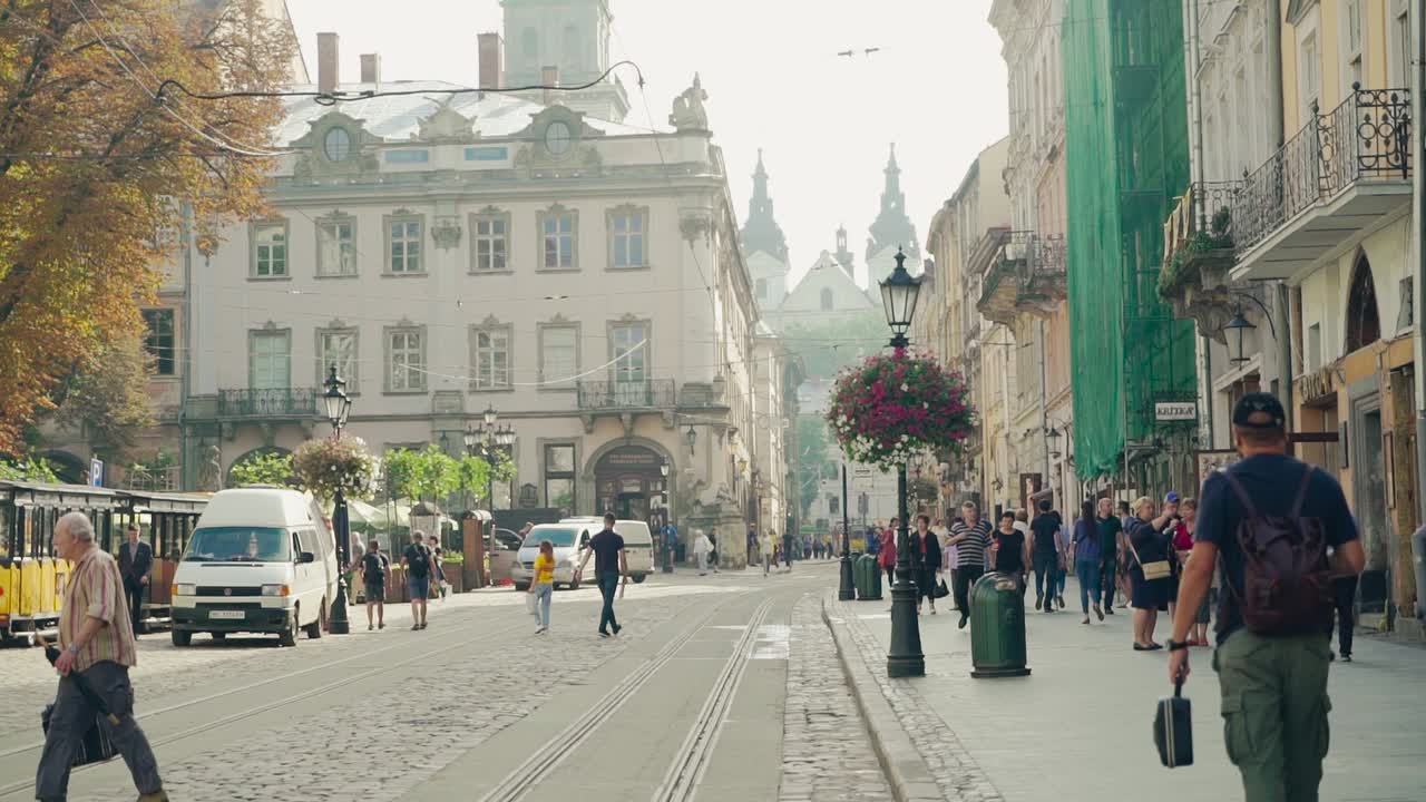 Central street of historical part of ancient city Lviv, Ukraine. Many tourists walking on the pavement with beautiful sightseeing of an old town.
