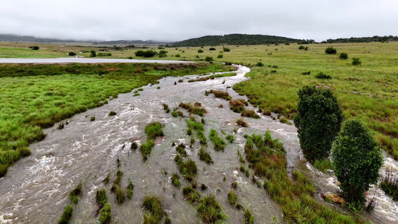 Dam capacity stretched to limit as one section of wall overflows on farm, aerial