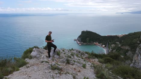 drone pilot on ridge directs flight over scenic coastal landscape, noli, italy