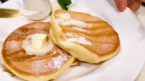 paints butter on famous dessert souffle pancake, japanese style in hong kong cafe restaurant