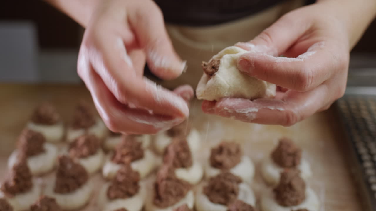 Baker's hands sculpt dumplings with meat filling