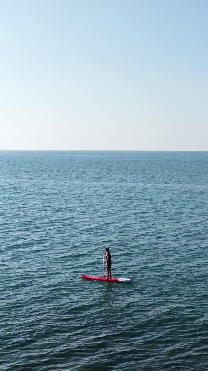 Man paddle boarding on calm sea. Vertical