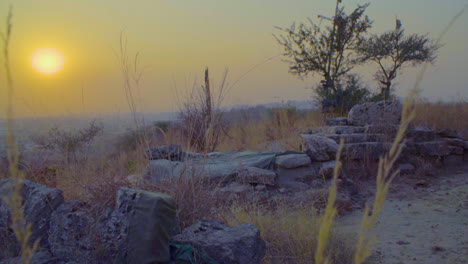 una vista del atardecer desde el primer plano de piedras y arbustos del pueblo, algunas banderitas en los árboles