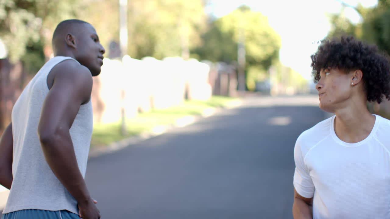 Jogging outdoors on sunny day, two multiracial male friends exercising together, copy space