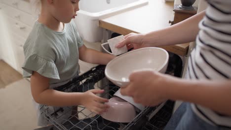 video of daughter helps to put dishes into a dishwasher.