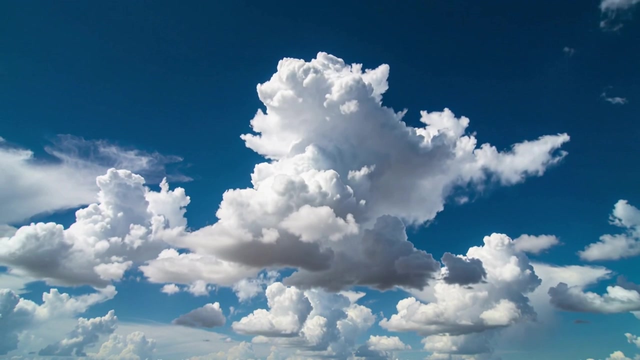 Growing central cumulus cloud rising and merging with horizon puffs as sun heats deep blue sky