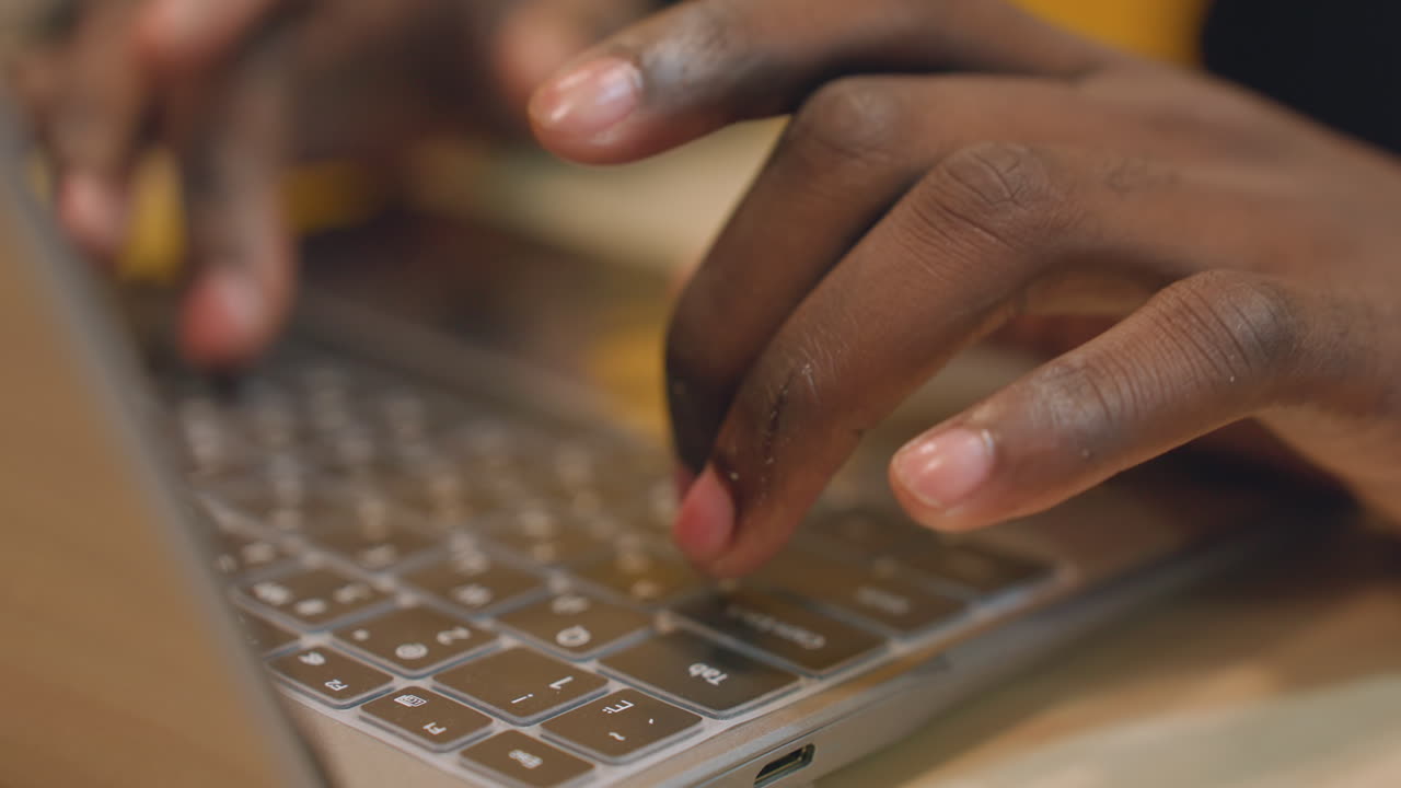 Persona che digita costantemente codice su un portatile luminoso in condizioni di scarsa illuminazione. Sviluppatore software concentrato impegnato in attività di codifica notturna utilizzando un computer illuminato in un ambiente tranquillo.