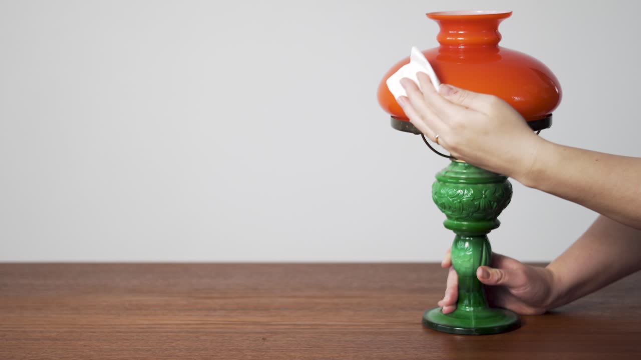 Revendedor(a) de artigos vintage inspeciona um abajur de mesa de meados do século, útil para conteúdo de brechó online, loja de antiguidades e negócios de artigos usados