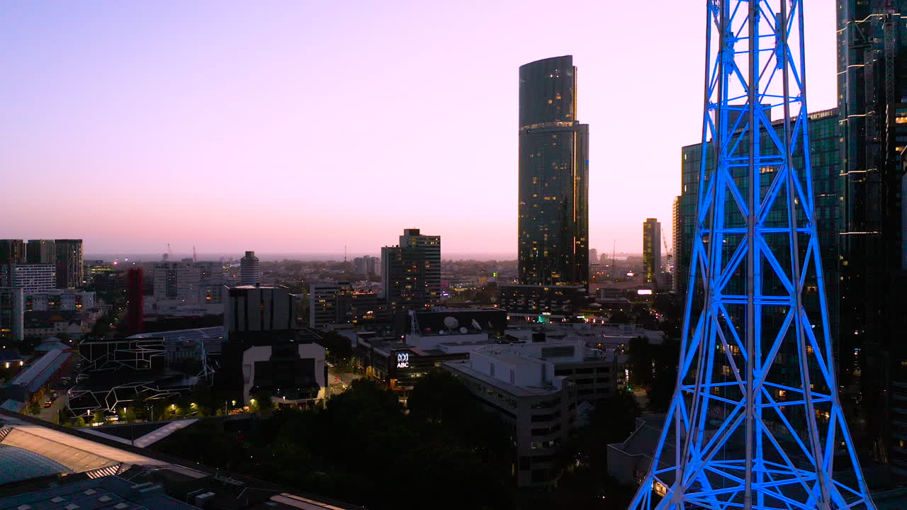 aguja de arte de melbourne resaltada con neón azul que brilla contra el hermoso horizonte de la ciudad al atardecer