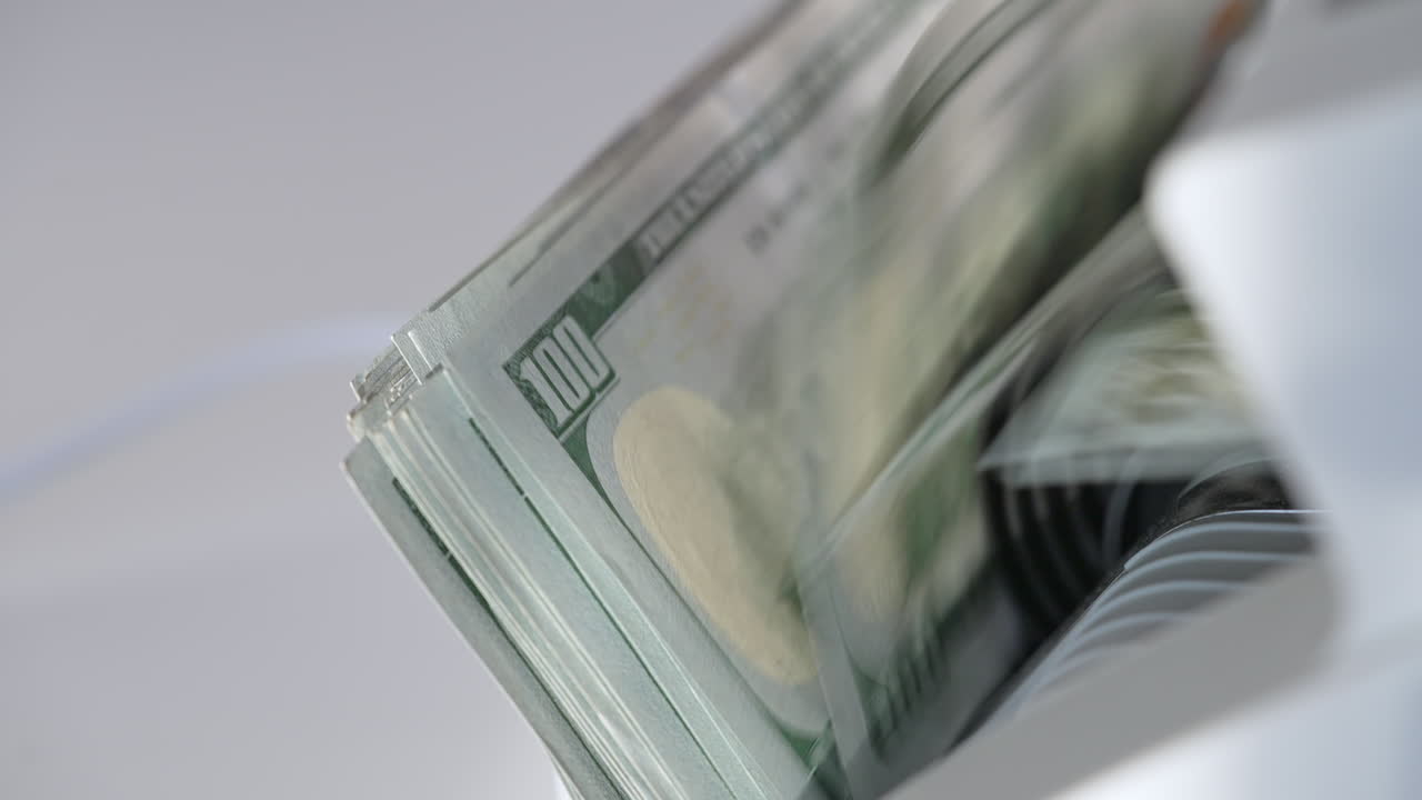 Pile of hundred dollar banknotes in the holder of cash machine. Close up. White background.