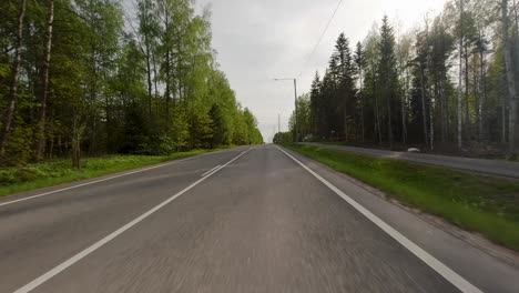 the road is adorned with lush green trees as it winds its way towards the village