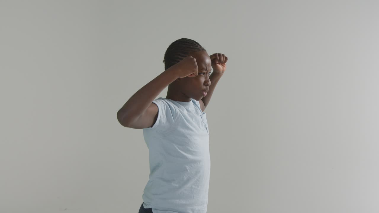 Photo en studio d'un jeune garçon montrant ses muscles sur fond blanc