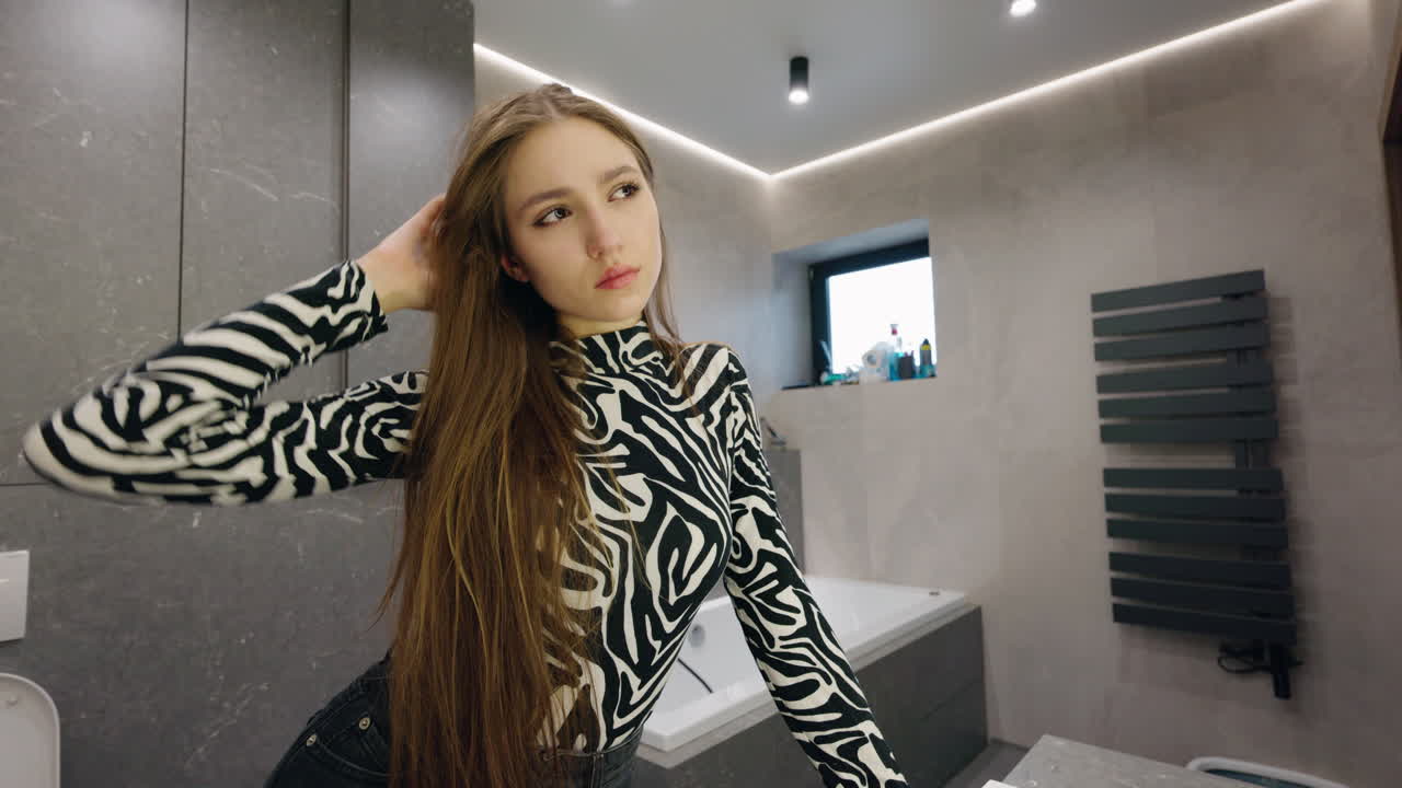 Woman Styling Hair in a Modern Bathroom