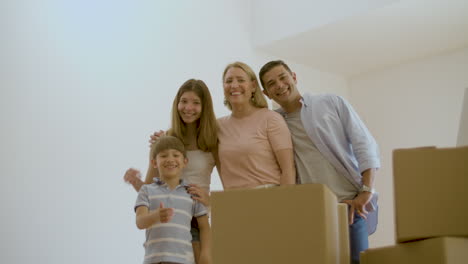 familia feliz de pie en la nueva casa y sonriendo a la cámara