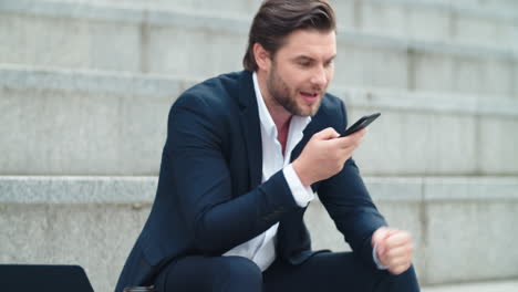 Businessman-talking-on-phone-loudspeaker-in-city.-Man-recording-voice-message