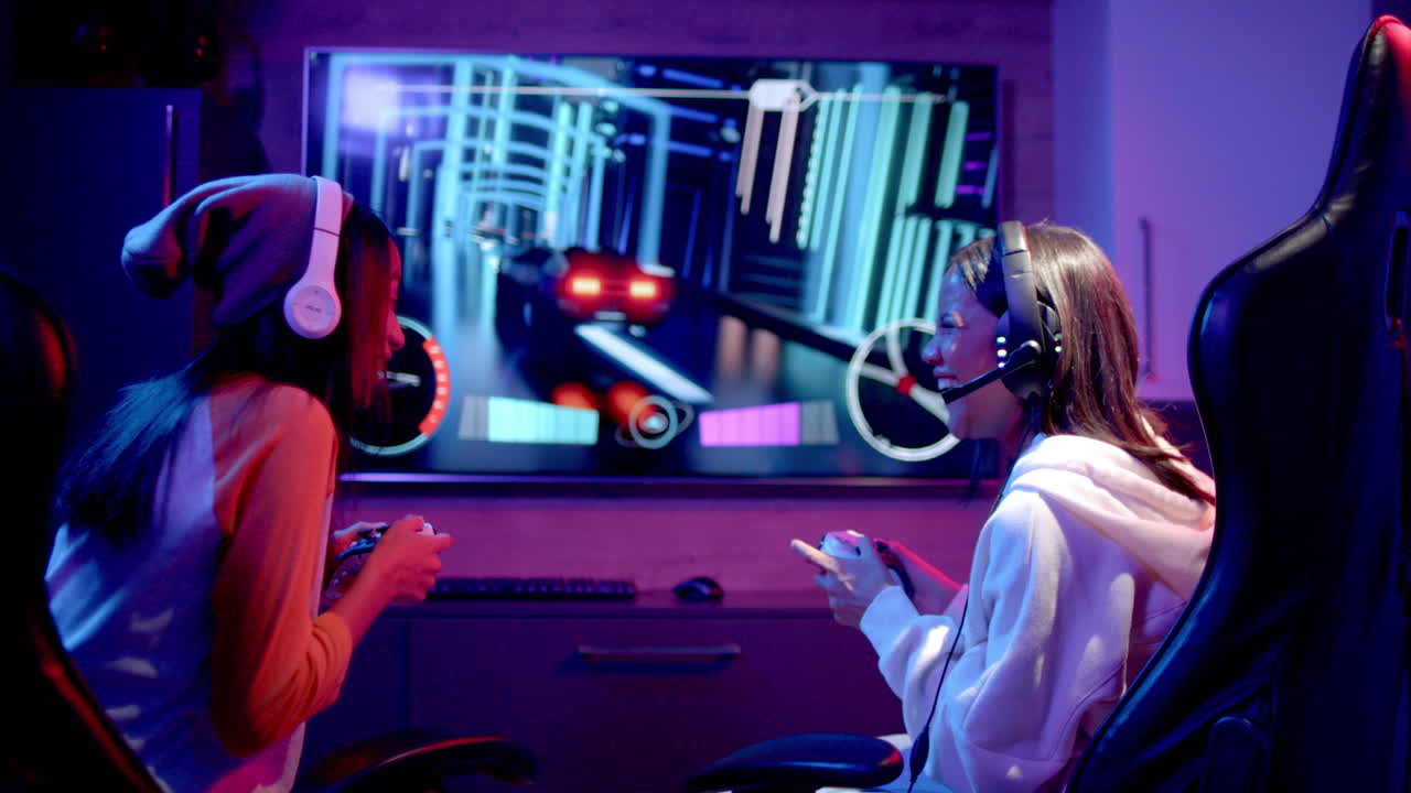 Playing video game, two teenage girls using controllers and wearing headphones