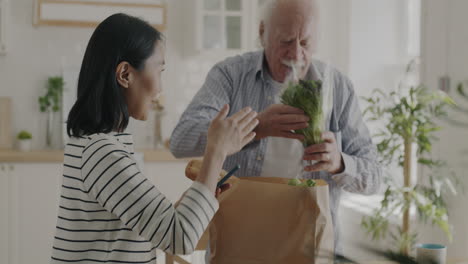 elderly man receiving grocery delivery help from a young woman