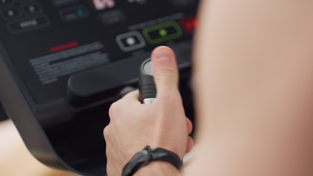 Firm grip on movable handle pressing control knob to adjust speed on elliptical trainer console in bright modern gym environment showcasing focused workout intensity adjustment under natural light