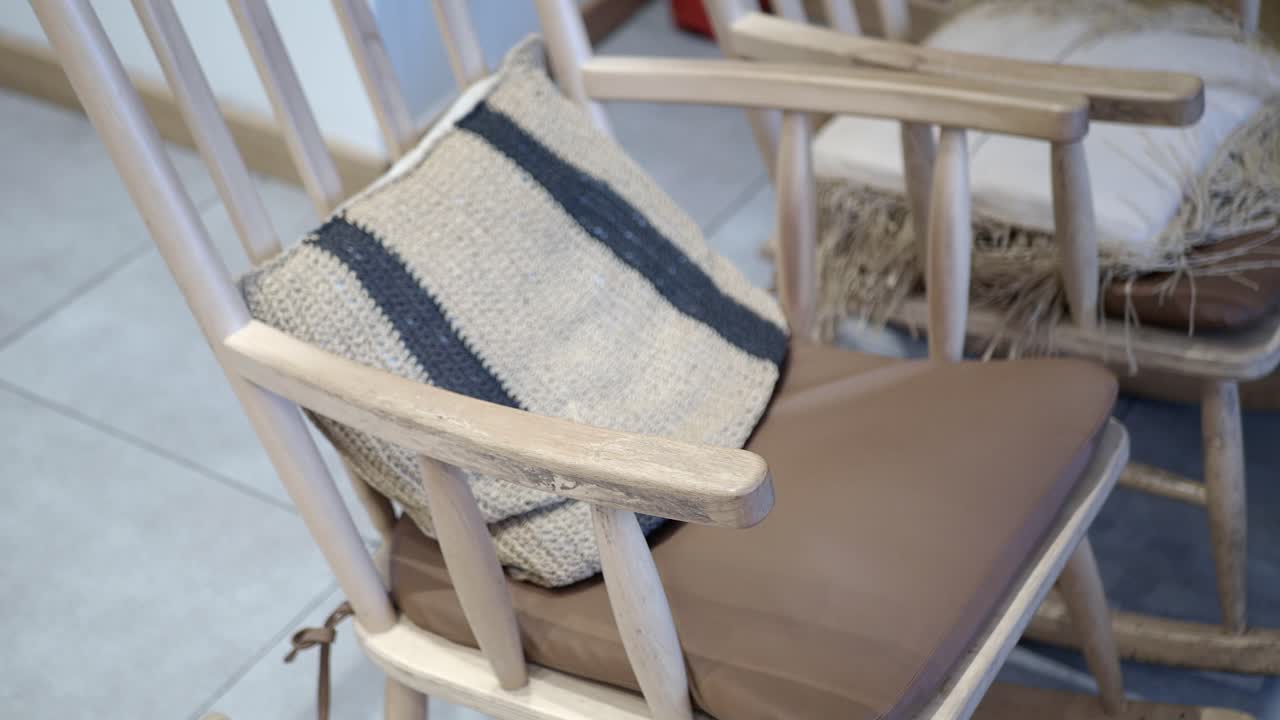 A wooden chair with a cushion and a patterned pillow