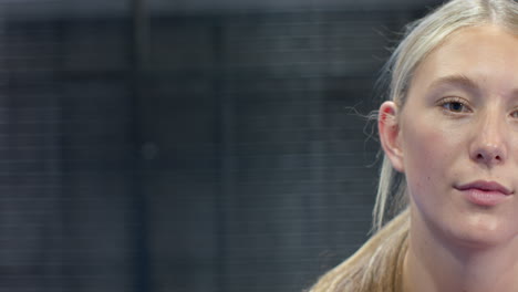 focused woman during padel tennis match, concentrating on game, at indoor court, copy space