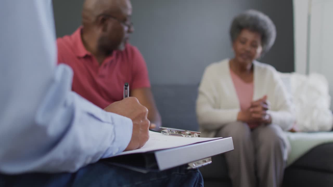 consejero masculino de raza mixta con clipboard aconsejando a un grupo de diversos amigos de edad avanzada