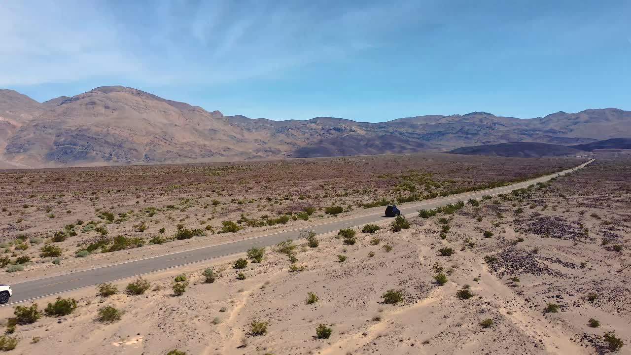 Veicoli in transito su strada attraverso il deserto arido nella Death Valley, California