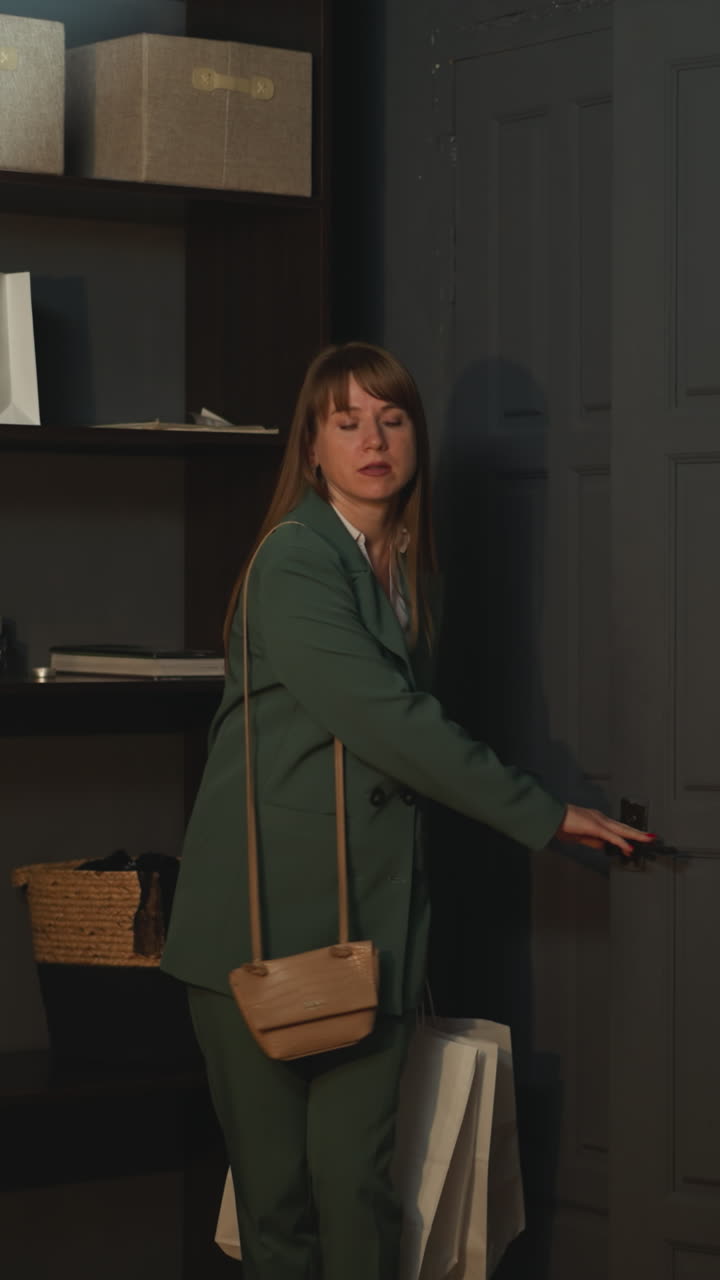 una mujer de negocios regresa a casa del trabajo sintiéndose agotada. una mujer solitaria entra en el pasillo oscuro llevando bolsas con compras. descansando en casa en la noche de un día de semana