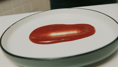 chef smears home made ketchup over a big plate