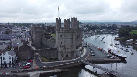 ancient caernarfon castle welsh harbour town aerial view medieval waterfront landmark pull away orbit left