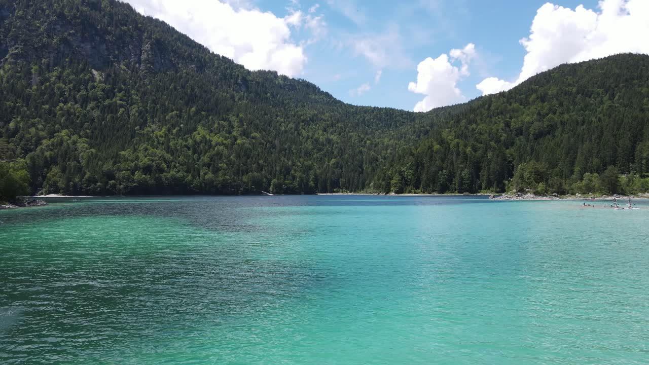 Vista aerea dell'Eibsee, un lago alpino turchese nelle Alpi bavaresi vicino allo Zugspitze, Germania. Acqua limpida di montagna, pendii boscosi e condizioni estive calme, ideali per viaggi e contenuti visivi naturalistici.