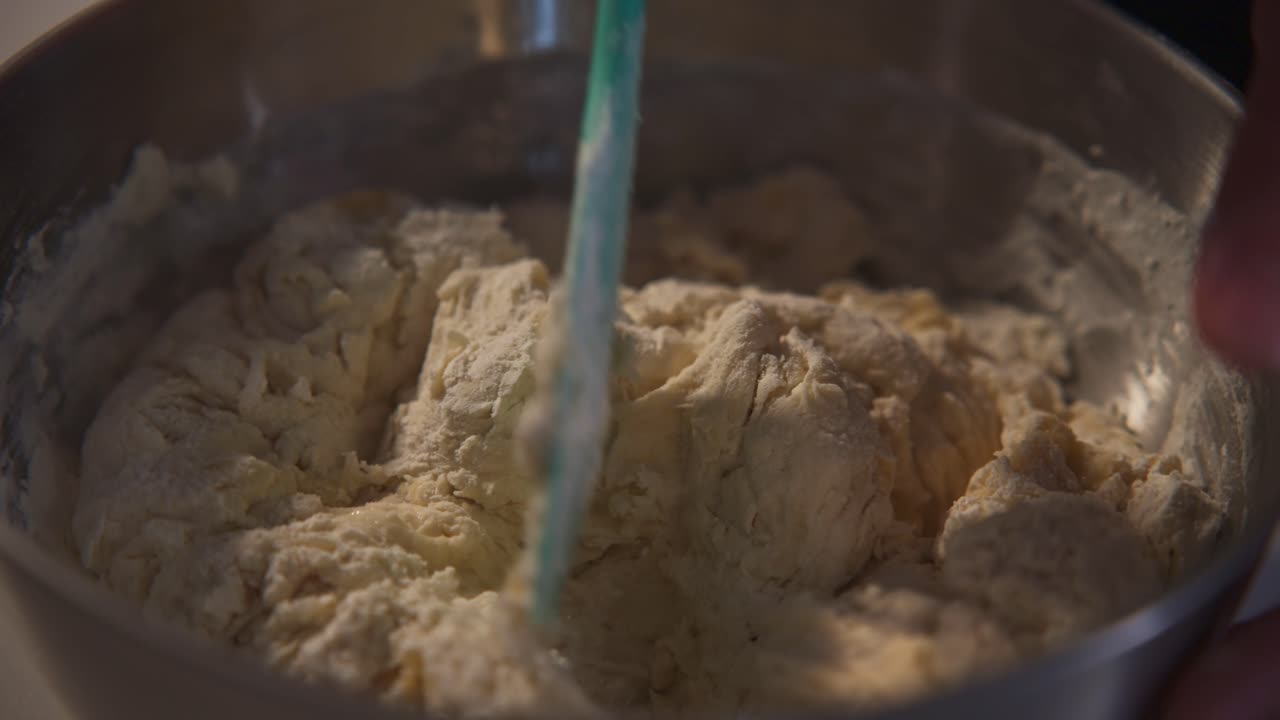 Close-Up of Hands Mixing Dough in a Bowl with a Spatula