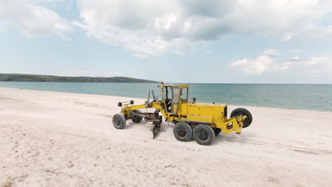 yellow grader working on beach