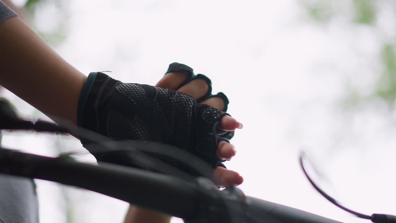 Quiet Roadside Moment With Cyclist Silhouette, Bare Hands Removing Gloves Against Backlit Bicycle Handlebar, Subtle Motion Captured Of Cyclist Removing Gloves Near Tranquil Roadside Background