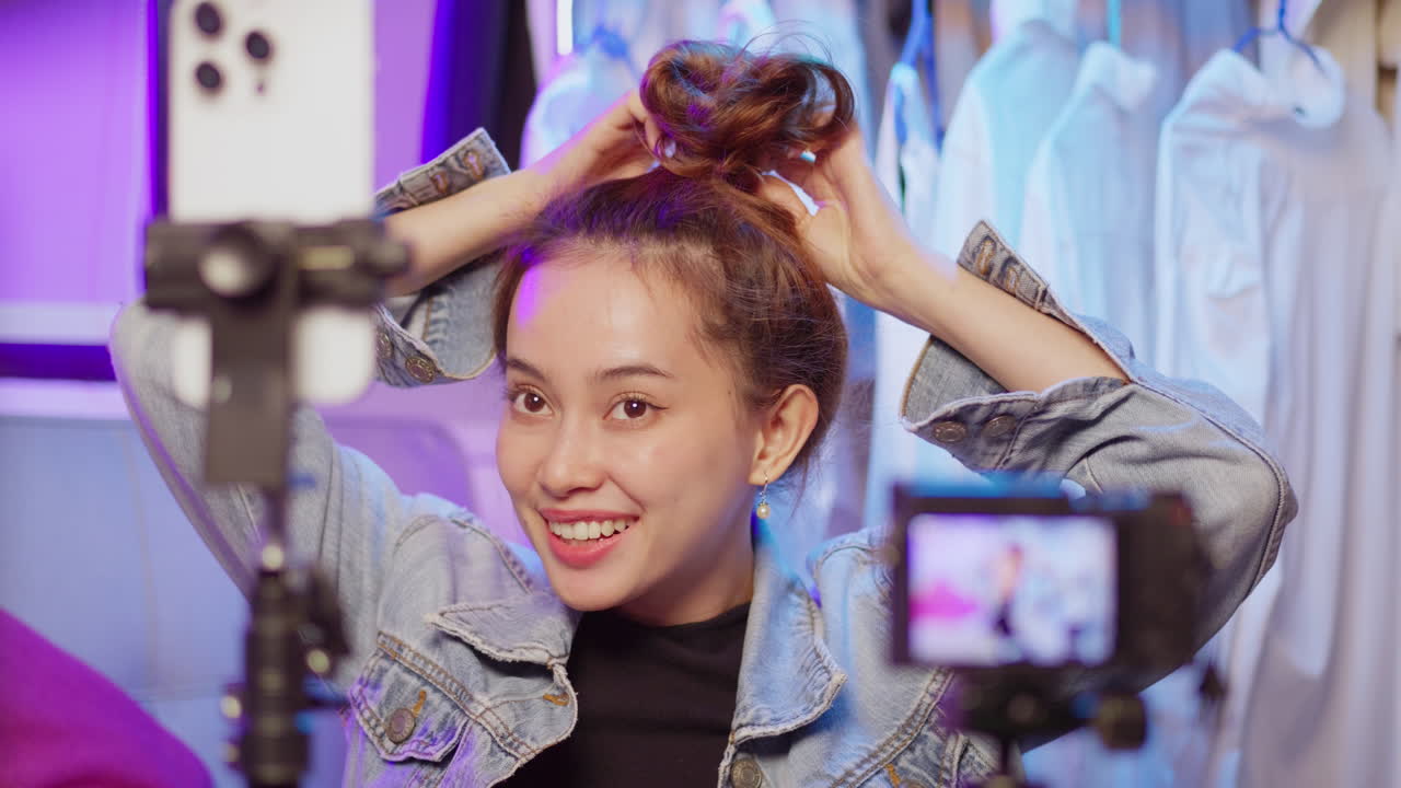 A young influencer captures a cheerful selfie in a vibrant studio filled with clothes.