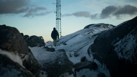 Hand-held-shot-of-a-hiker-climbing-up-the-snowy-Lovstakken-mountain-at-sunrise