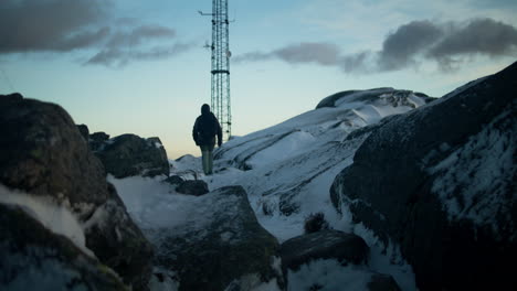 hand-held shot of a hiker climbing up the snowy lovstakken mountain at sunrise