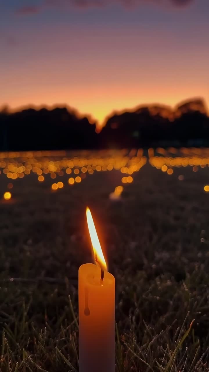 Klidná svíčka plápolající při západu slunce, zachycená z nízkého úhlu, ideální pro uklidňující video.