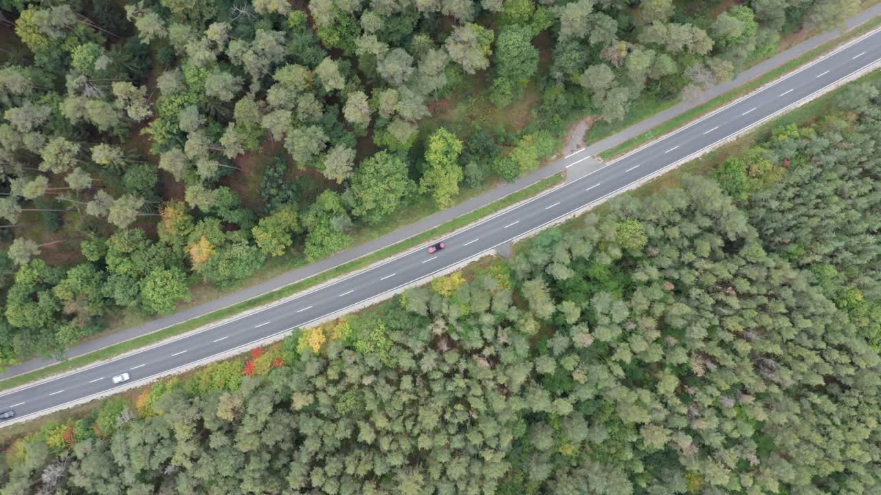 Slow aerial spin, camera looking down at a road through a forest, 4k