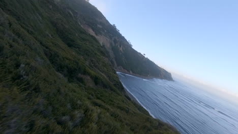 Siguiendo-Los-Contornos-Del-Paisaje-A-Lo-Largo-De-Los-Acantilados-Que-Dominan-La-Playa-En-Una-Vista-En-Primera-Persona-De-Un-Dron-De-Carreras