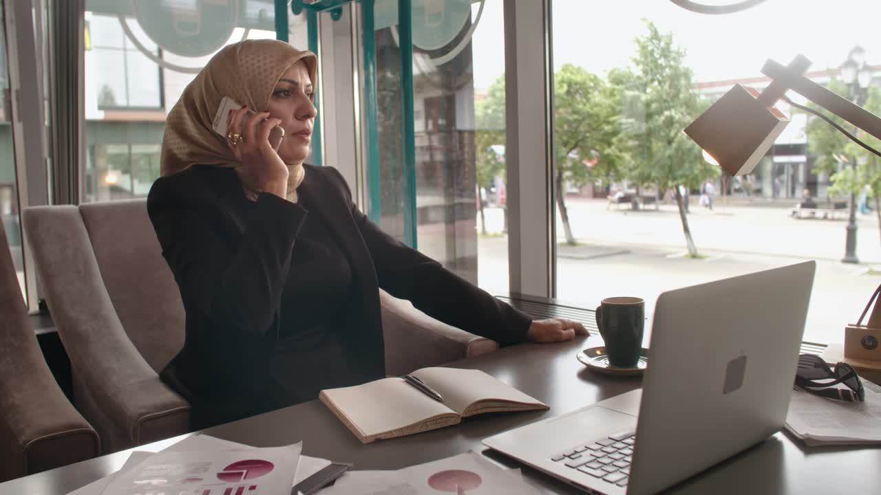 Mellemøstlig forretningskvinde taler i telefon på café