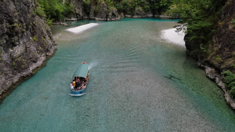 Toma-Aérea-Sobre-El-Lago-Komani-Y-Seguimiento-Cercano-De-Un-Barco-Que-Se-Acerca-A-La-Orilla-Del-Lago