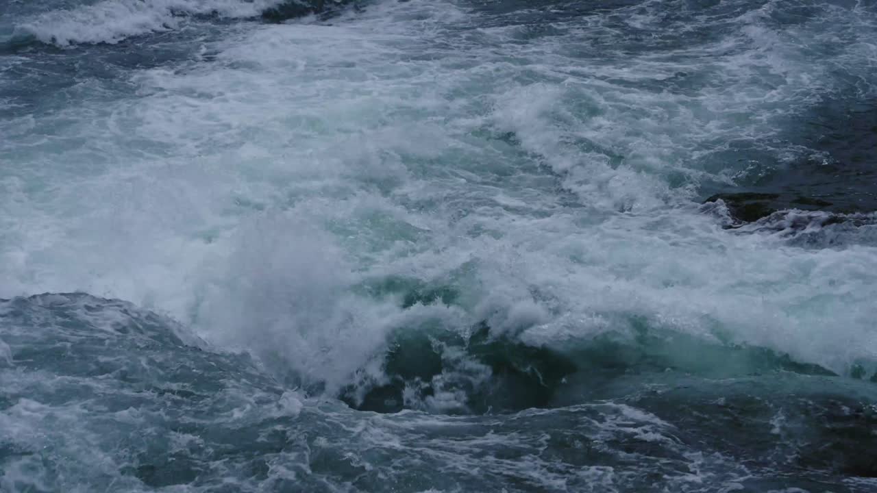 Close-up view of intense whitewater rapids crashing and swirling over rocks, capturing the raw power and turbulence of a wild river current